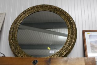 An ornate gilt circular framed mirror