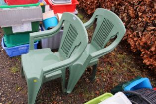 Four green plastic stacking garden chairs