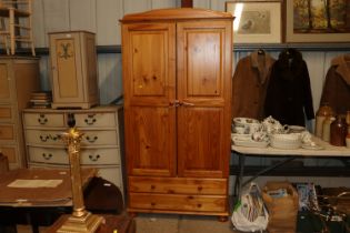 A pine two door wardrobe fitted two drawers below