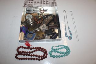 A tin containing a compass, various badges, bead n