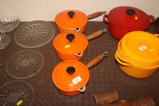 Three orange Le Creuset saucepans and lids