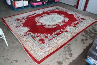 An approx. 11'11" x 9'2" red patterned rug