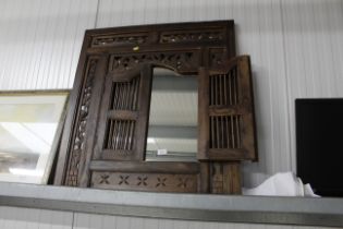 A rustic style mirror enclosed by a pair of spindl