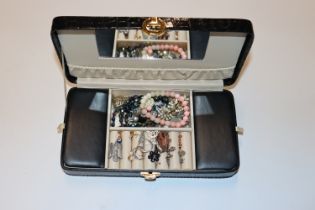 A black jewellery box with contents of various cos