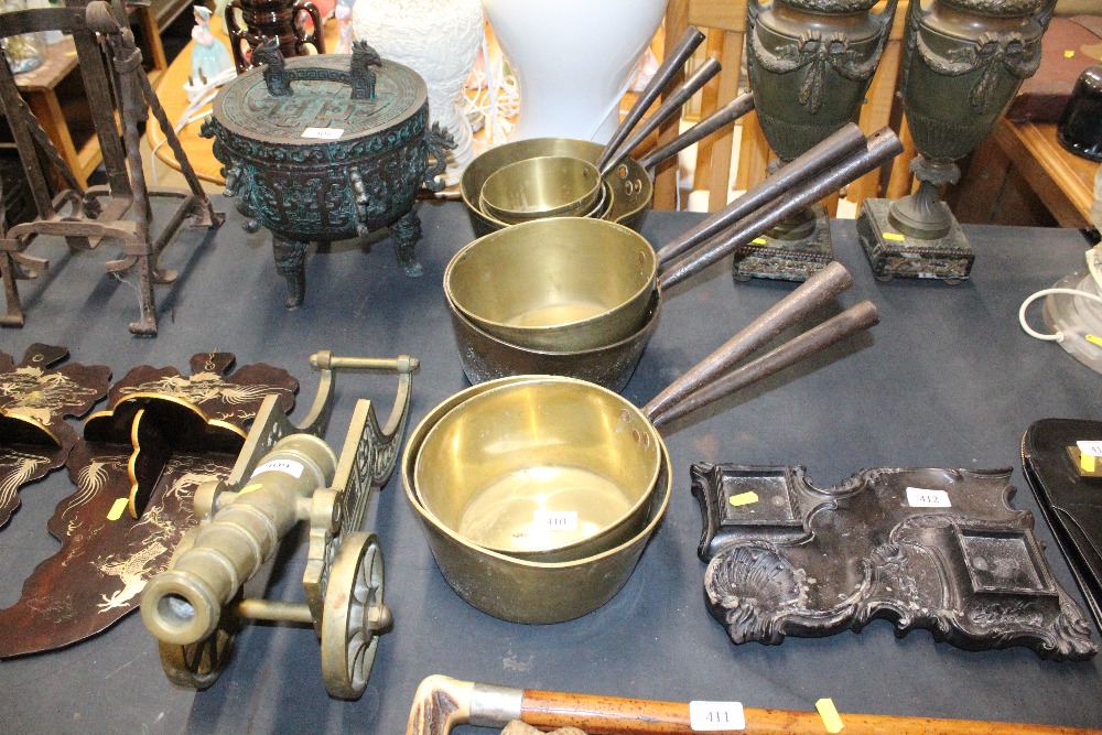 A quantity of graduated brass saucepans