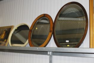 Two wooden framed bevel edged oval wall mirrors to