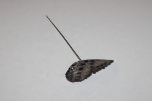 A hat pin in the form of a birds wing decorated wi