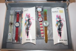 A metal case containing four Swatch watches