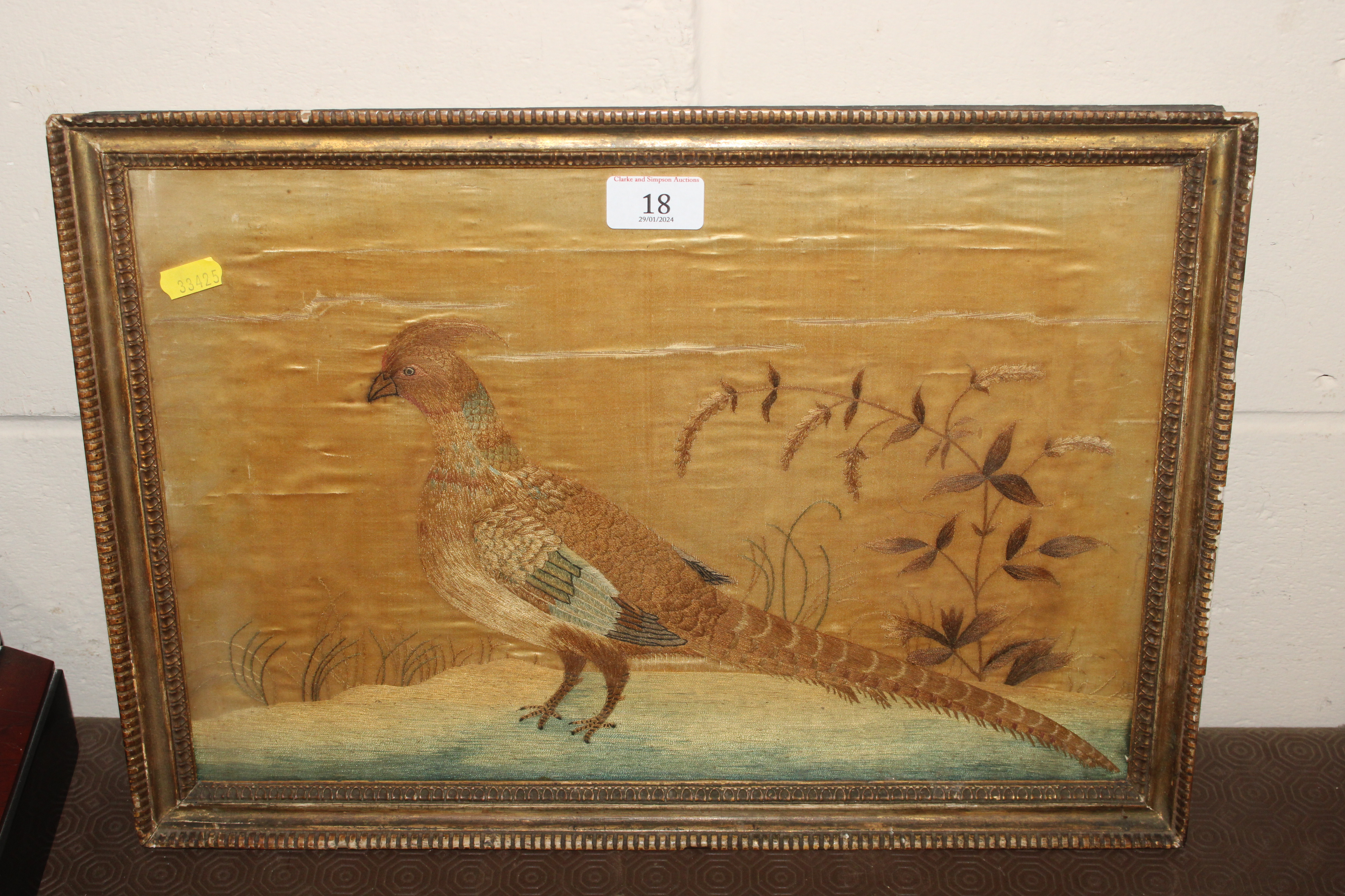 A needlework study of a golden pheasant contained