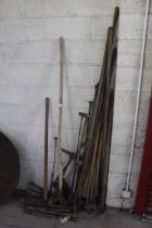 A large quantity of long handled tools including sheep dipping tools, drag fork, hoes etc.