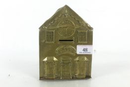 A brass embossed money box in the form of a bank