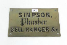 A brass sign for "Simpson Plumber, Bell Hanger & C