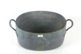 A large copper twin handled cooking pot of oval fo