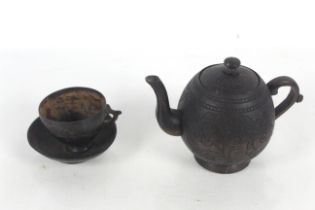 A coconut carved teapot, cup and saucer