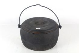 A oval cast iron 4 gallon cooking pot with swing handle and lid by Clarke & Co.