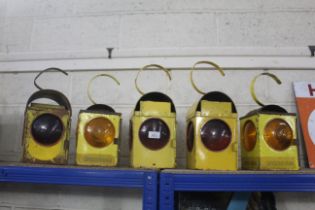 Five various sized yellow road lamps