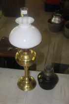 A brass oil lamp with opaque glass shade and a fur