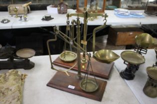 Two sets of brass balance scales set to wooden pli