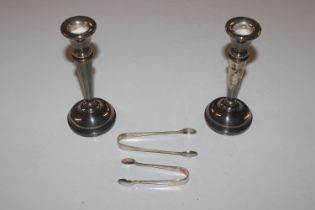 A pair of silver candlesticks with weighted bases and two pairs of silver sugar tongs
