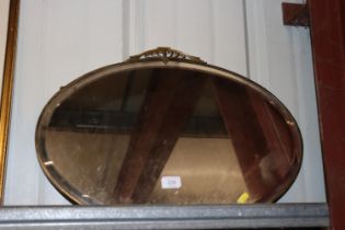 A brass framed oval Art Deco designed bevel edged