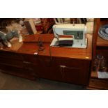 A Singer sewing machine with teak cabinet, sold as