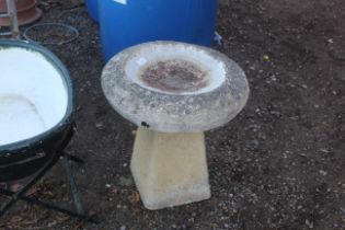 A circular concrete bird bath raised on plinth