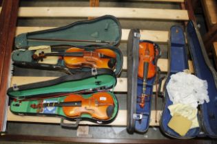 Three violins with bows and a violin case