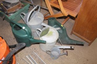 Three galvanised watering cans and two plastic wat