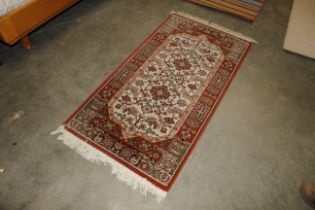 An approx. 5'3" x 2'6" floral patterned wool rug
