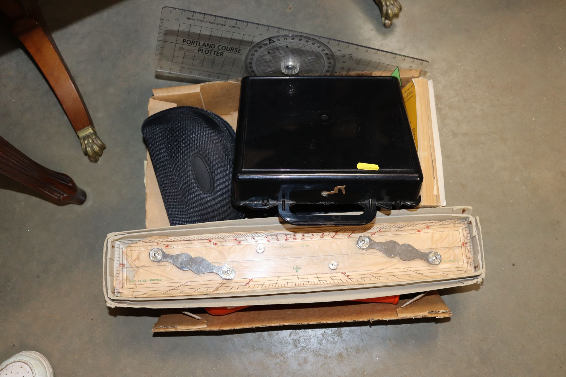 A box containing various navigational equipment including a sextant and sunglasses