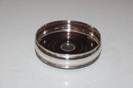A silver bottle coaster with turned wooden base