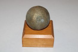 An unusual brass canon ball on a wooden stand