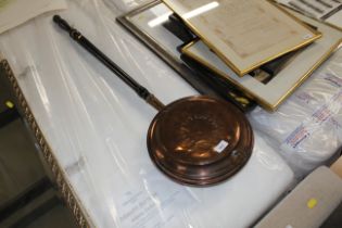 An antique copper warming pan with turned ebonised