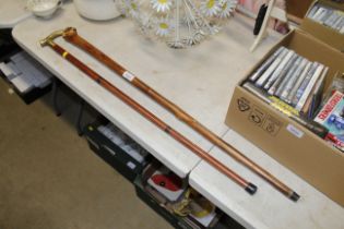 A rustic walking stick and another with brass hand