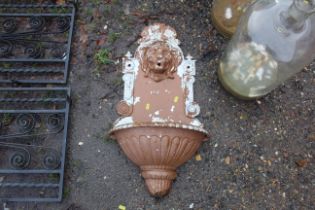 An ornate wall mounting planter with lions head de