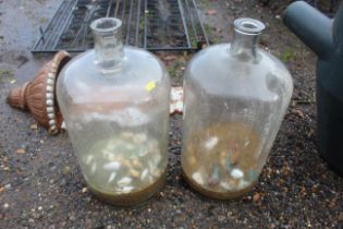 Two large glass bottles partly filled with sand an