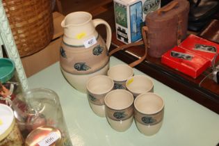 A Holkham pottery jug and five pottery cups
