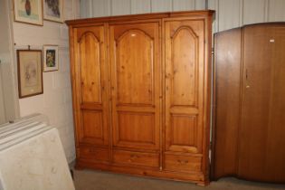 A triple pine wardrobe fitted three drawers below