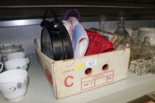A box containing place mats, oven gloves, clock et
