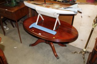 An oval mahogany pedestal coffee table with brass