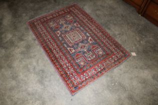 An approx. 4'4" x 3' red and blue pattern wool rug
