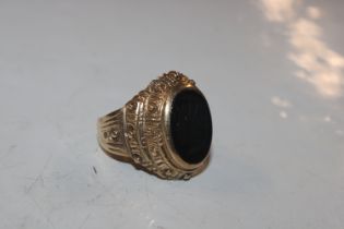 A 9ct gold ring set with black stone having carved