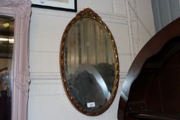 An oval gilt framed bevel edged wall mirror