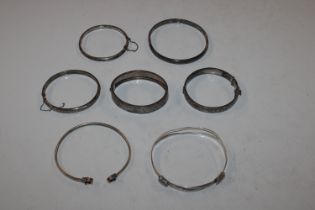 A box of silver and white metal bangles (7)