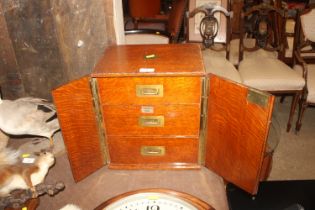 An Army & Navy oak table top three drawer cabinet