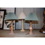 A pair of turned wooden table lamps and another