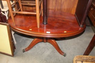 An oval mahogany coffee table raised on brass claw