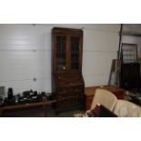 An oak bureau bookcase with coloured glass and leaded front fitted with three long drawers