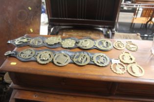 A collection of horse brasses, some on leather str