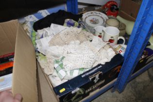 A box containing various table cloths, lace, towel